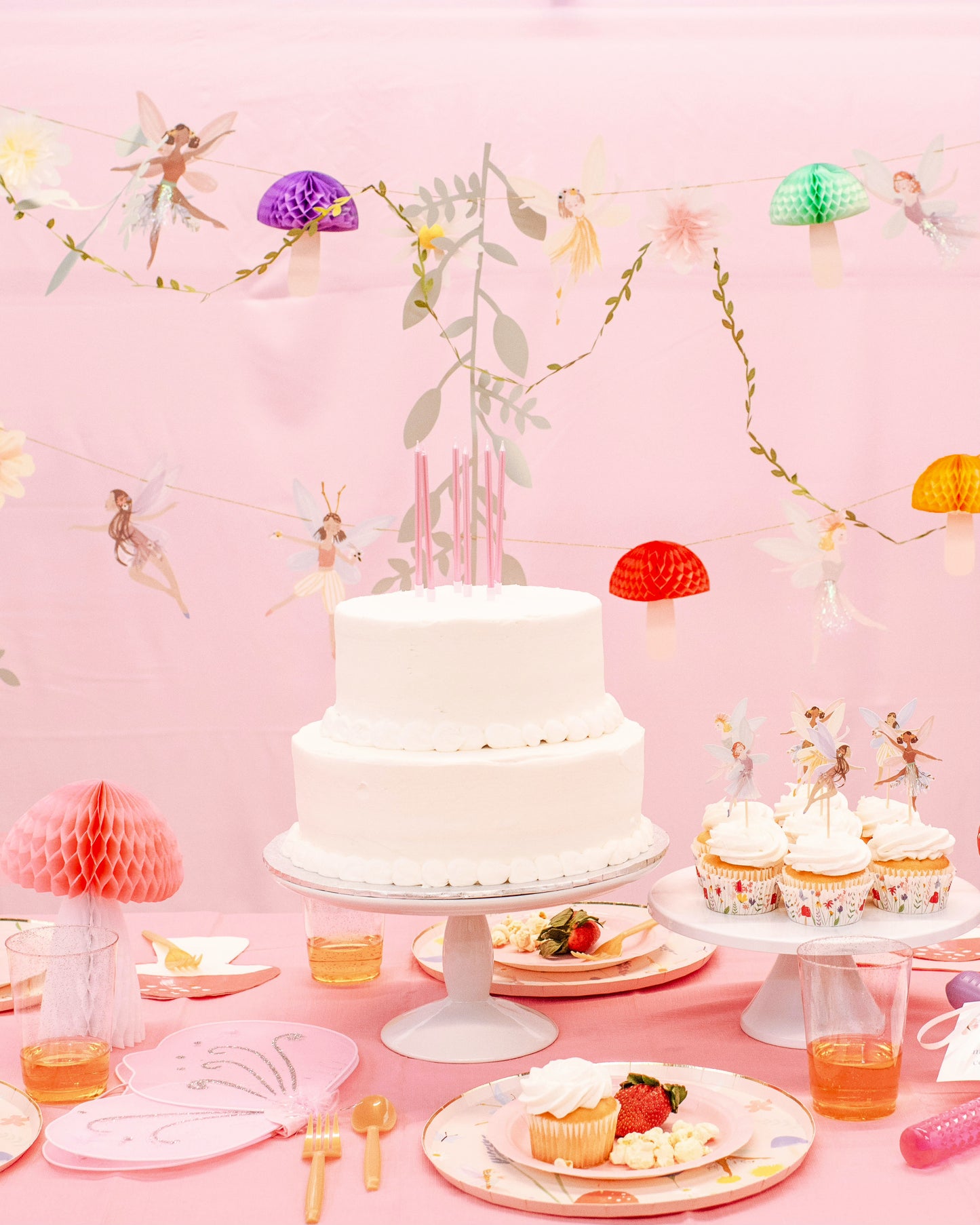 Whimsical fairy party table setup with soft pastels, mushroom centerpieces, and woodland accents