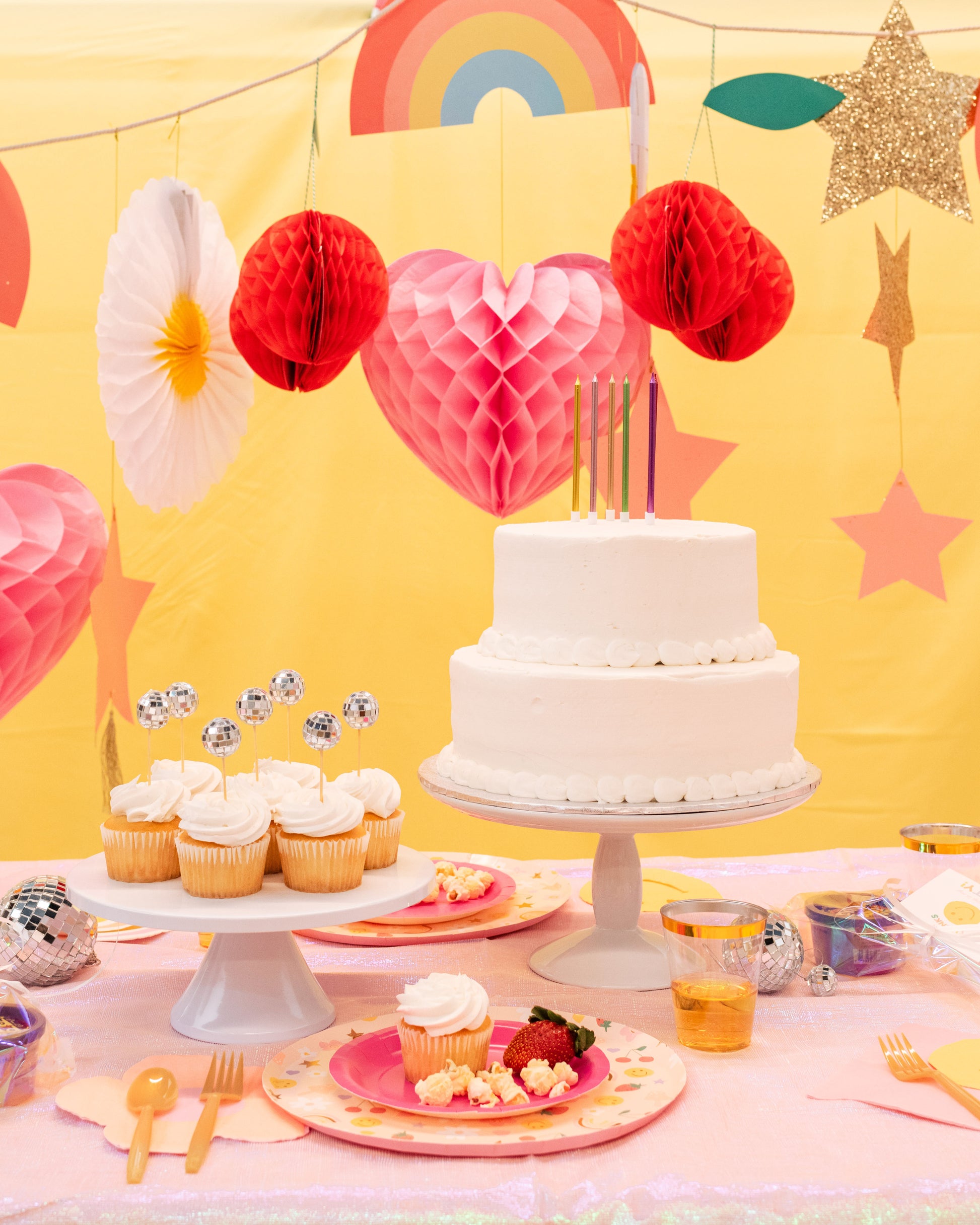 Kids groovy birthday table setup with icon plates, gold rimmed cups, and 70s-inspired decorations