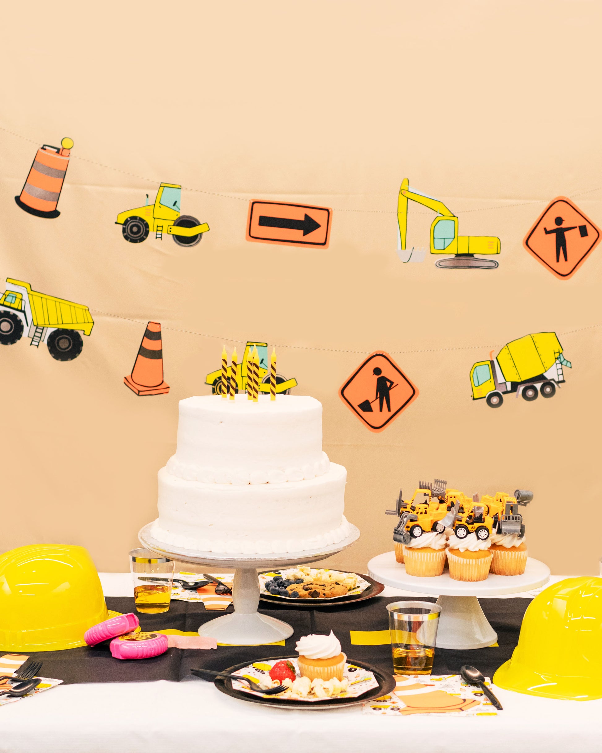 Kids construction birthday party table with orange cones and digger plates